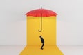 A conceptual image of a man staring at a floating red umbrella on a vibrant yellow background, depicting protection and