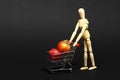 Conceptual image of a miniature shopping trolley filled with apples