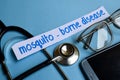 Mosquito - borne disease inscription with the view of stethoscope, eyeglasses and smartphone on the blue background