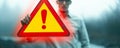 Conceptual image of a person holding a floating exclamation mark in a warning triangle, symbolizing caution, alertness, and