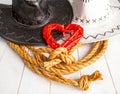 Conceptual image of rural wedding of cowboys. White bride hat and dark groom hat and red heart symbol of love