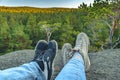 Conceptual image of two pairs of legs in sneakers against the background of forest rock. Casual unisex sneakers and jeans on