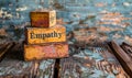 Conceptual image of vintage wooden blocks stacked with the word Empathy on a rustic table against a worn blue wall, depicting