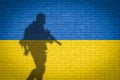 Conceptual image of war between Russia and Ukraine with shadow of soldier against wall with flags