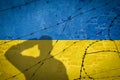 Conceptual image of war between Russia and Ukraine with shadow of soldier against wall with flags