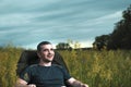 Conceptual image of watching movies in modern technologies, a young man sits in a comfortable chair on the nature under the open