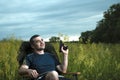 Conceptual image of watching movies in modern technologies, a young man sits in a comfortable chair on the nature under the open