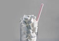 Conceptual macro still life image of refreshment glass full of sugar cubes and straw on white background in glucose addic