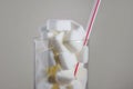 Conceptual macro still life image of refreshment glass full of sugar cubes and straw on white background in glucose addic