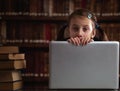 Conceptual mage: The largest library is a digital library. Portrait of young beautiful girl sitting in library and learning with