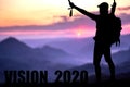 Conceptual message writing showing `vision 2020`. The young mountaineer managed to climb to the top and achieve his goal.