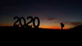 Conceptual message writing showing `2020`. The young mountaineer managed to climb to the top and achieve his goal.