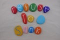 Refuse to sink, motivational phrase composed with colored stones over white sand