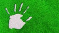 Conceptual ornamental gravel handprint on grass background