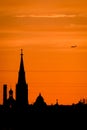 Conceptual photo of city downtown at sunset with skyline silhouette against a beautiful orange sky a airplane. Defocused Royalty Free Stock Photo