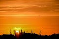 Conceptual photo of city downtown at sunset with skyline silhouette against a beautiful orange sky a airplane. Defocused Royalty Free Stock Photo