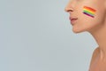 Conceptual photo of female face with colorful painted rainbow on cheek. LGBT flag. Equality and support of diversities to people