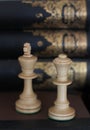 Conceptual photo. Chess pieces on a book in a library with books on the bookshelf background. Chess piece photography. Remote off