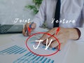 Conceptual photo about JV Joint Venture with written acronym. Senior Man Checking A Document on background Royalty Free Stock Photo