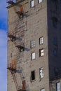 Conceptual photo of the old factory building. A concrete ugly structure with external metal stairs and various broken windows. Royalty Free Stock Photo