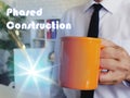 Conceptual photo about Phased Construction with Man with a cup of coffee in the background