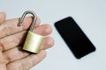 Conceptual photo of security on mobile phones. Hand holding a open padlock and a cell phone in the background Royalty Free Stock Photo