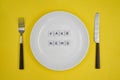 Conceptual photo, table setting with an empty plate, fake news consumption by the public or consumers- `Fake news` on yellow backg