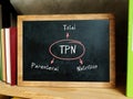 Conceptual photo about TPN Total Parenteral Nutrition . Blank small chalkboard and different school stationery on wooden table