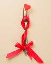 Conceptual photo, valentine`s day greeting card. A fork with a ribbon and a pierced heart. Love symbol