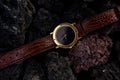 Conceptual photography luxury watch. Gold brown black watch on magma rock background