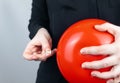 Conceptual photography. The woman holds a red ball near his belly, which symbolizes bloating and flatulence. Then she brings a nee