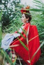 Conceptual portrait of beautiful young woman with red lips, red flowers in hair, sitting in wheel chair.