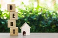 Conceptual about property debt. A small house model with stack of wooden block on nature background. Depicts debt resulting from Royalty Free Stock Photo