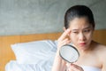 Portrait of Asian woman worry about her face when she saw the problem of wrinkle and age spots by the mini mirror. Royalty Free Stock Photo