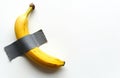 Conceptual still life featuring banana fixed to wall using duct tape. Modern art object mimics creative, absurd installation. Royalty Free Stock Photo