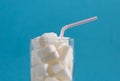 Conceptual still life image of glass full of sugar cubes and straw in excess of calories in soft drinks Royalty Free Stock Photo