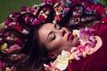 Conceptual studio portrait girl. Artificial flowers and a green background