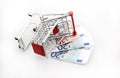 Conceptual studio shot of a bunch of euro banknotes filling a shopping cart on white background september 18, 2016