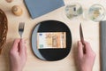 Conceptual studio shot of dinner table with euro bank notes on the plate instead of food. Concept for rising food prices Royalty Free Stock Photo