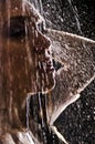 Conceptual view and scene of a young, sensual, beautiful girl, a woman who washes in the shower under a powerful jet of water in Royalty Free Stock Photo