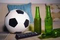 Conceptual watching football game at sofa on television with beer bottles and popcorn bowl in friends enjoying soccer game TV