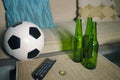 Conceptual watching football game at sofa on television with beer bottles and popcorn bowl in friends enjoying soccer game TV