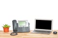 Conceptual workspace or business office concept. Laptop computer with modern IP phone, plant in a pot and computer mouse on light Royalty Free Stock Photo