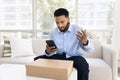 Concerned annoyed young African costumer man using smartphone Royalty Free Stock Photo