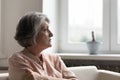 Concerned anxious senior 60s woman looking away, sitting on couch