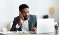 Concerned businessman talking on cellphone and looking at laptop screen Royalty Free Stock Photo