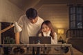 Concerned couple looking at a laptop screen in a softly lit room, both man and woman appears stressed