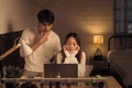 Concerned couple looking at a laptop screen in a softly lit room, both man and woman appears stressed
