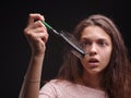 Girl struggling with tangled hair on the black background. Close-up woman looking at a comb with hair. Balding concept. Royalty Free Stock Photo