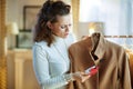 Concerned elegant woman examines sale price tag on beige coat